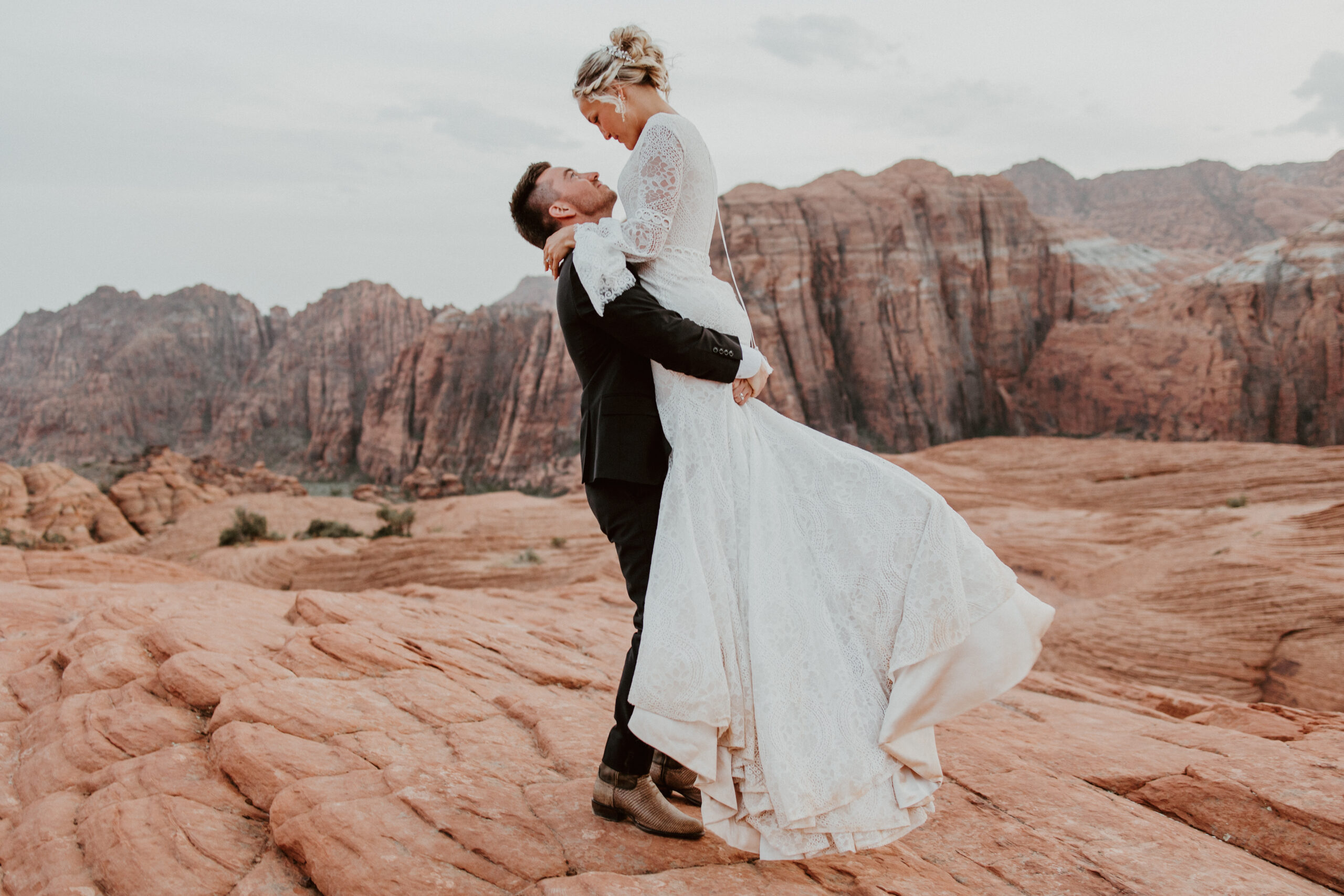groom holding bride red rock