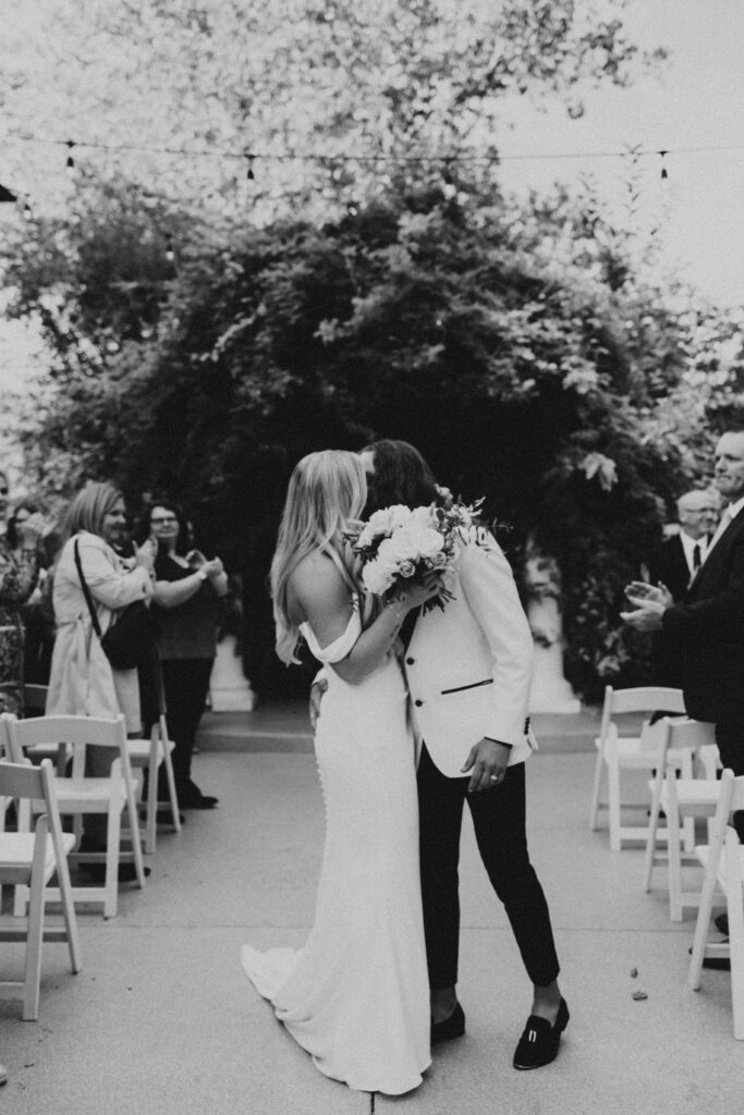 couple's first kiss down the aisle with guests clapping