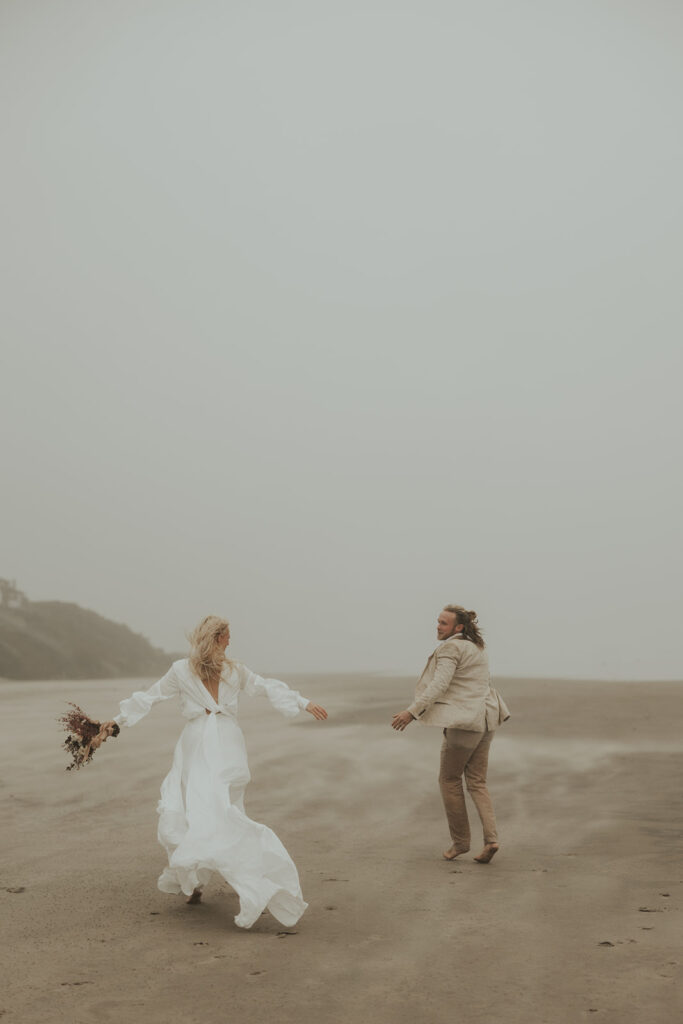 couple laughing running around the beach 