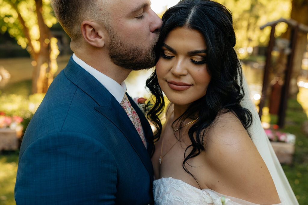 cute picture of the groom kissing the bride on the forehead 